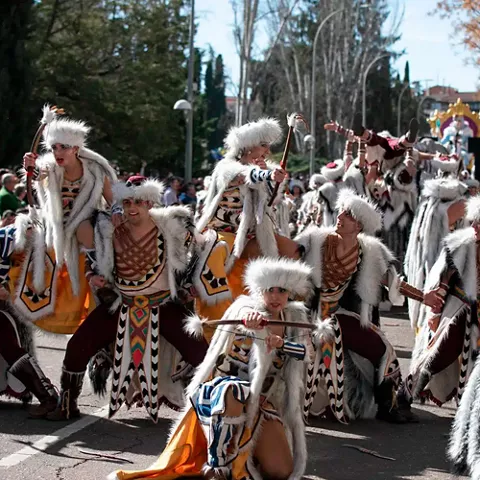 Grupo de bailarines con trajes de inspiración tribal realizando una coreografía en la calle.