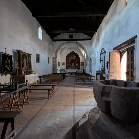 Nave interior con pila bautismal y altar al fondo.