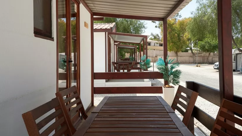 Porche de bungalow con mesa de madera y sillas