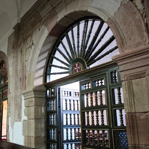 Puertas interiores de madera y forja bajo arcos de piedra.