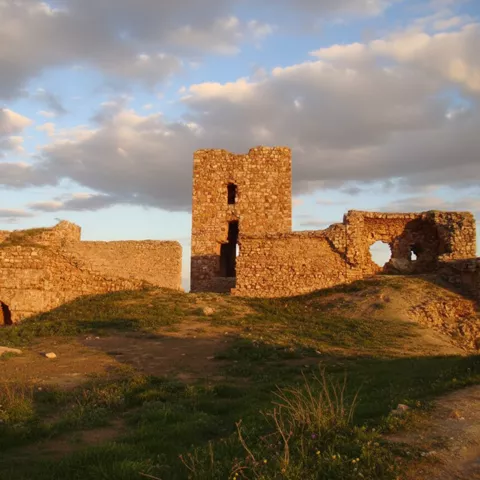 Restos del castillo de Caracuel de Calatrava iluminados por la luz dorada del atardecer.