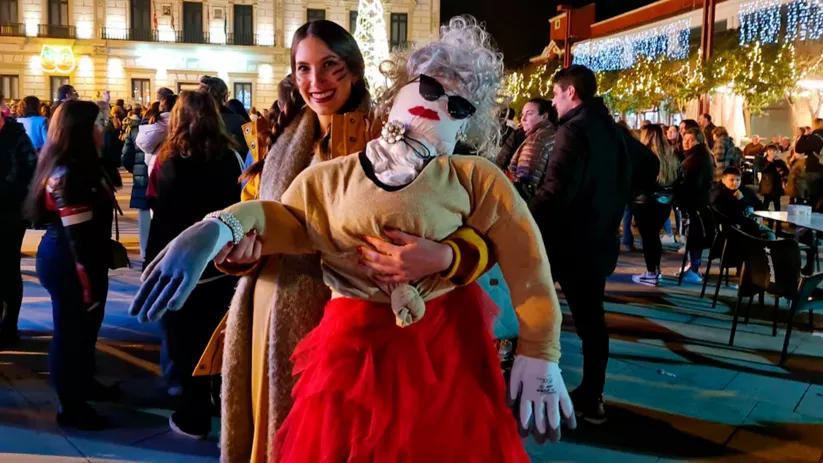 Persona posando con muñeco disfrazado en celebración nocturna