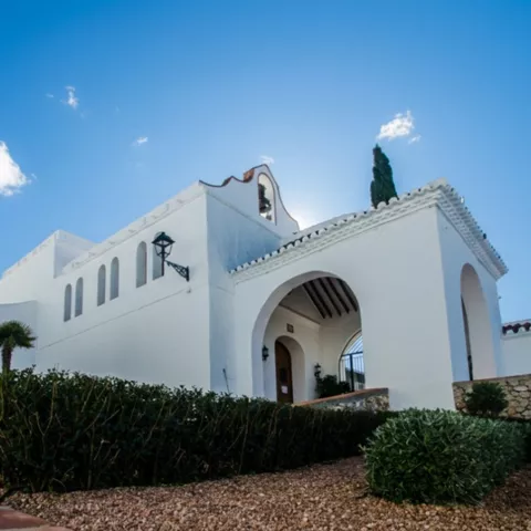 Construcción blanca con arco y jardín cuidado
