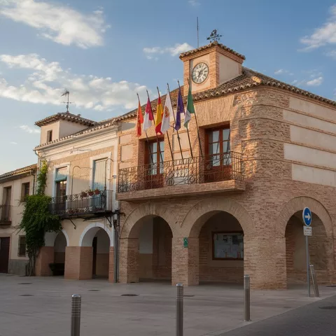 Fachada del Ayuntamiento de Carrión de Calatrava con soportales y banderas oficiales.