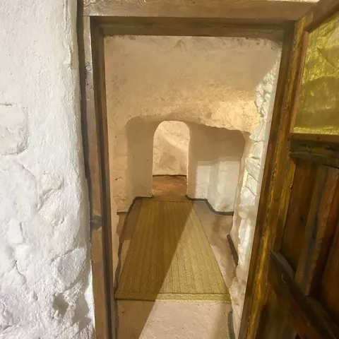 Pasillo subterráneo con muros encalados y arco excavado