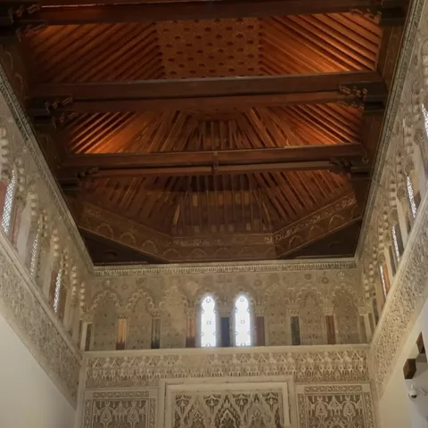 Gran sala con muros ornamentados y techo artesonado de madera.
