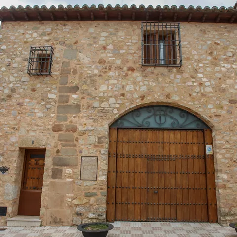Casa tradicional de piedra con gran portón de madera y ventanas enrejadas.