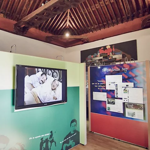 Espacio museístico con paneles temáticos, pantalla y estructura de madera.