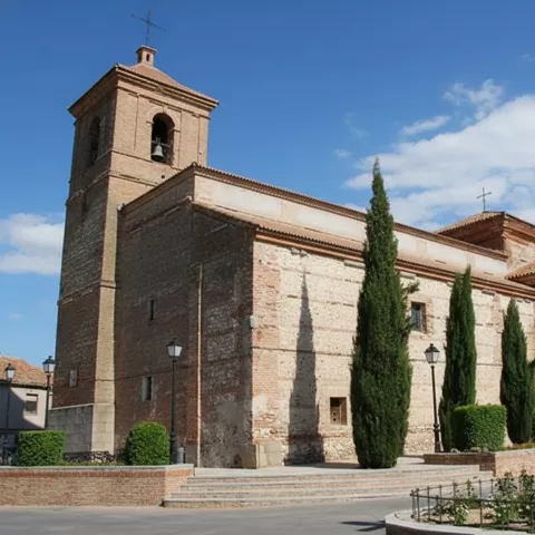 Iglesia de ladrillo con torre y cipreses