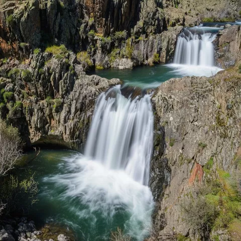 Caída de agua sobre poza turquesa.
