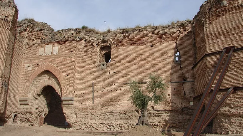 Lienzo de muralla de ladrillo con torre y refuerzos metálicos