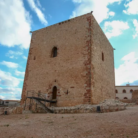 Castillo de piedra con murallas y acceso principal.