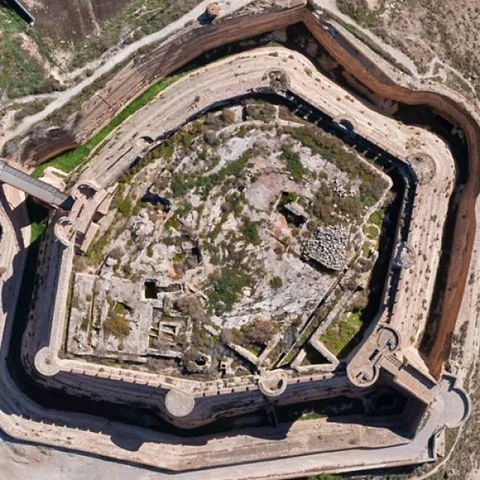 Vista aérea superior de una fortaleza rodeada por murallas y caminos