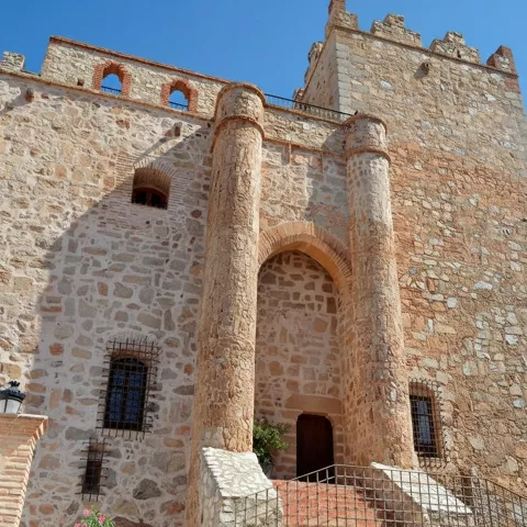 Vista frontal de fortaleza de mampostería con torre cuadrada y escalinata de acceso.