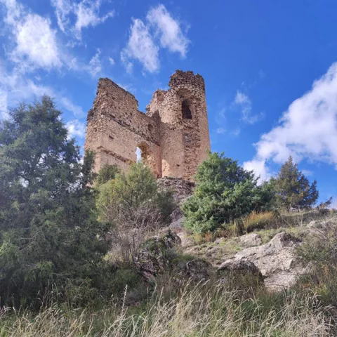 orre medieval en lo alto de una ladera rocosa.