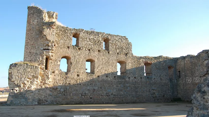 Patio interior de fortaleza en ruinas con muros gruesos y vanos rectangulares.