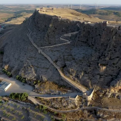 Vista aérea de una fortaleza en lo alto de una meseta, con el pueblo a sus pies.