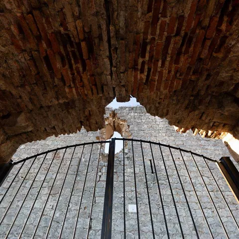 Un acceso con una puerta y un muro de piedra.