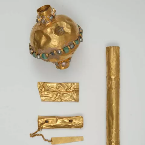 Conjunto de piezas de oro y láminas decoradas dispuestas sobre fondo neutro.