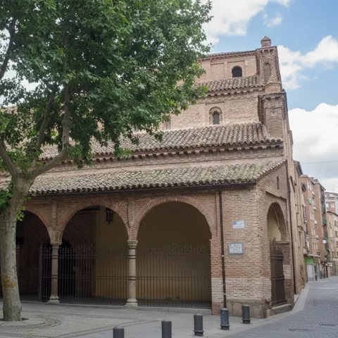 Iglesia de ladrillo con arcos y plaza arbolada