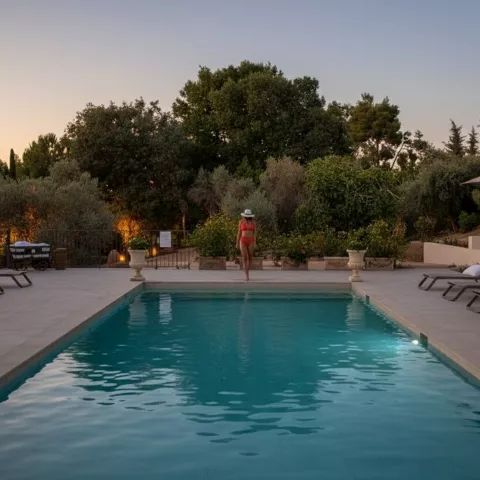 Piscina iluminada al anochecer con tumbonas a ambos lados.