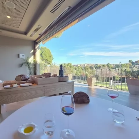 Mesa preparada con vino y terraza con paisaje al fondo