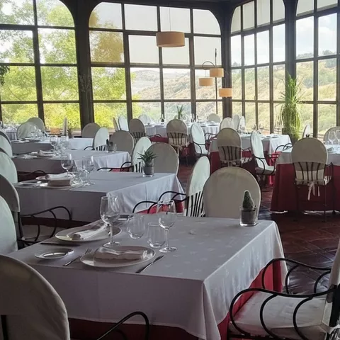 Comedor luminoso con ventanales altos y mesas preparadas.