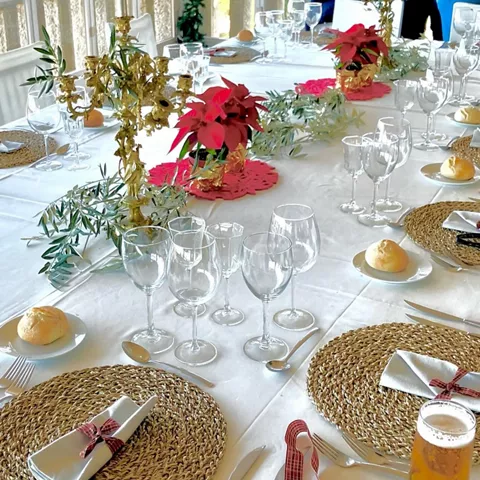 Mesa larga decorada con flores rojas y copas