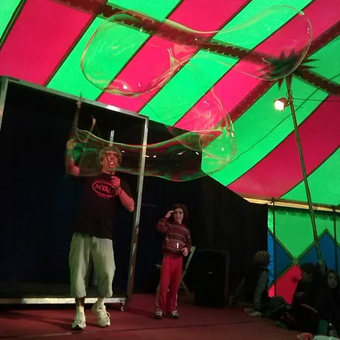 Espectáculo infantil de pompas gigantes bajo una carpa de colores