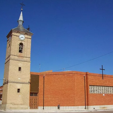 Iglesia de ladrillo con torre y cruz bajo cielo azul