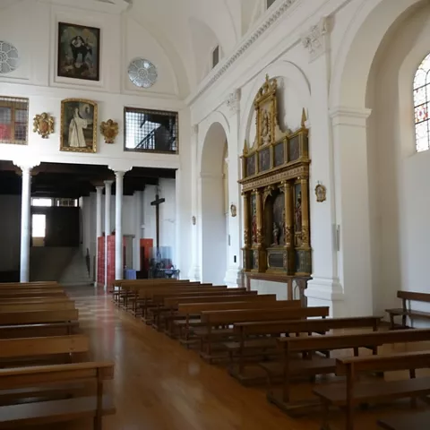 Interior de iglesia con bancos de madera y retablo lateral