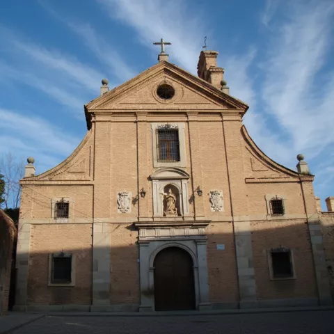 Fachada principal de iglesia de ladrillo con hornacina central y puerta de arco.