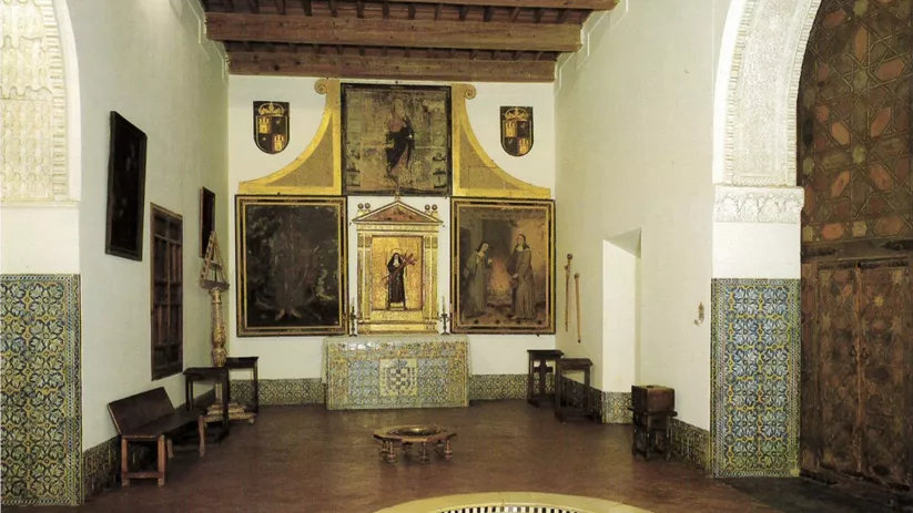 Sala con artesonado, altar al fondo y azulejos decorativos en las paredes.