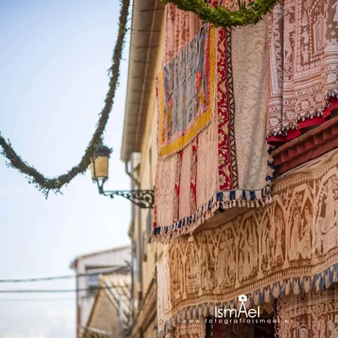 Tapices decorativos colgados en balcones de una calle festiva