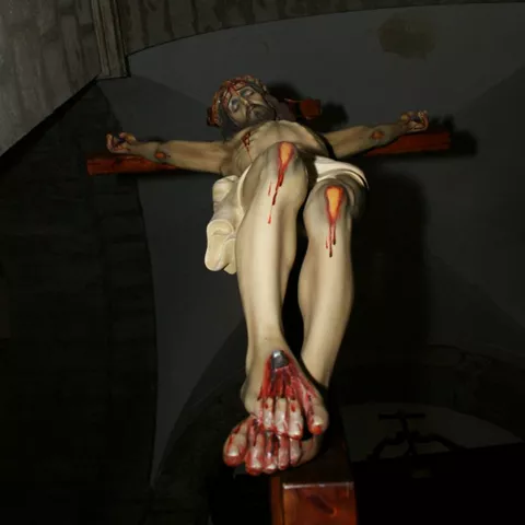 Escultura religiosa crucificada iluminada en interior