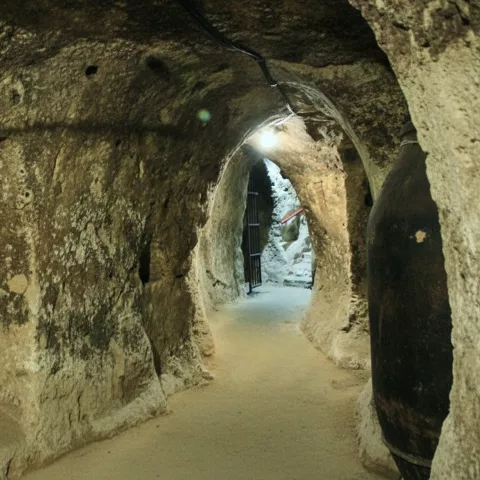 Pasadizo excavado en roca con iluminación artificial.