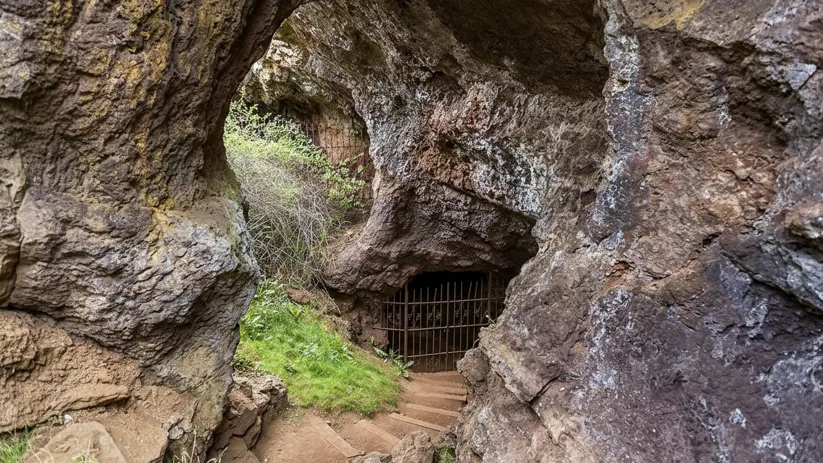 Acceso rocoso con escaleras y reja metálica