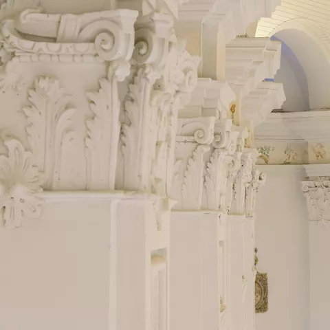 Detalle de columnas ornamentadas en espacio expositivo blanco.