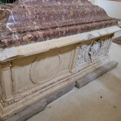 Sepulcro monumental de mármol con decoración histórica.