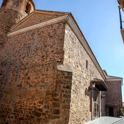 Vista lateral de iglesia de piedra junto a una calle.