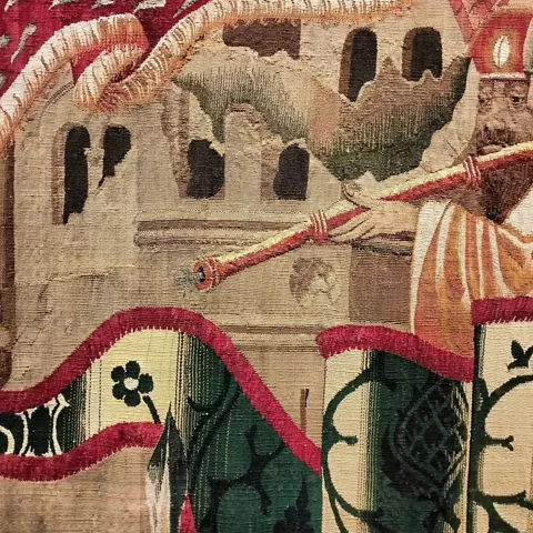 Detalle de tapiz histórico con muralla y arquitectura medieval