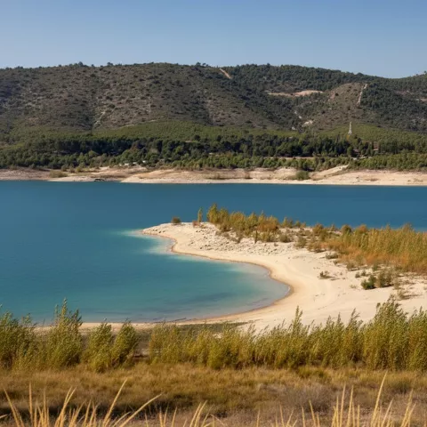 Playa de arena en embalse rodeado de colinas
