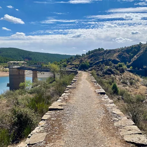 Sendero junto a embalse y montaña.