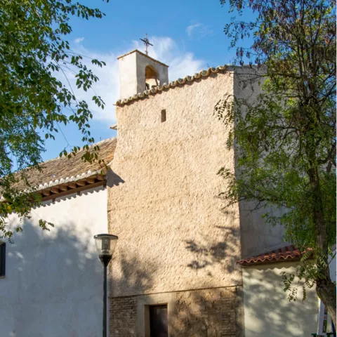 Muro lateral de iglesia con campanario y banco