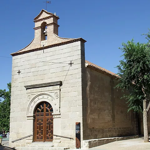 Fachada de edificio religioso de piedra junto a una calle