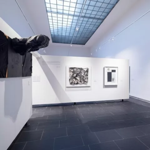 Galería con obras contemporáneas y pieza textil en relieve.