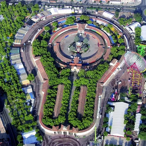 Vista aérea de recinto circular rodeado de arbolado y atracciones.
