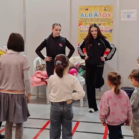 Monitoras frente a un grupo de niños en una actividad dentro de un recinto ferial.