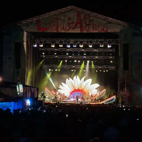Concierto nocturno con escenario decorado y espectáculo de luces ante numeroso público.