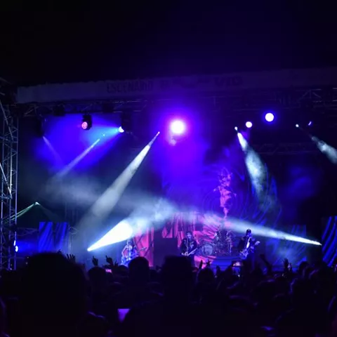 Concierto nocturno con luces y público levantando las manos